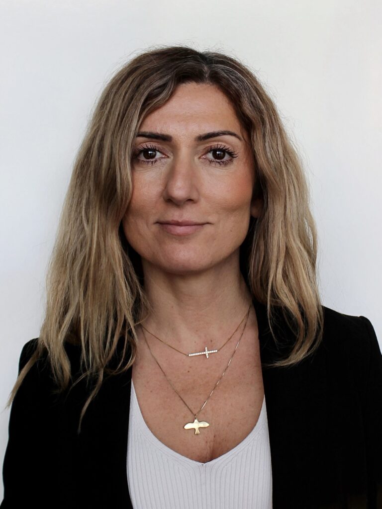 Porträtt av AKG VD med långt brunt hår och svart kavaj mot ljus bakgrund.