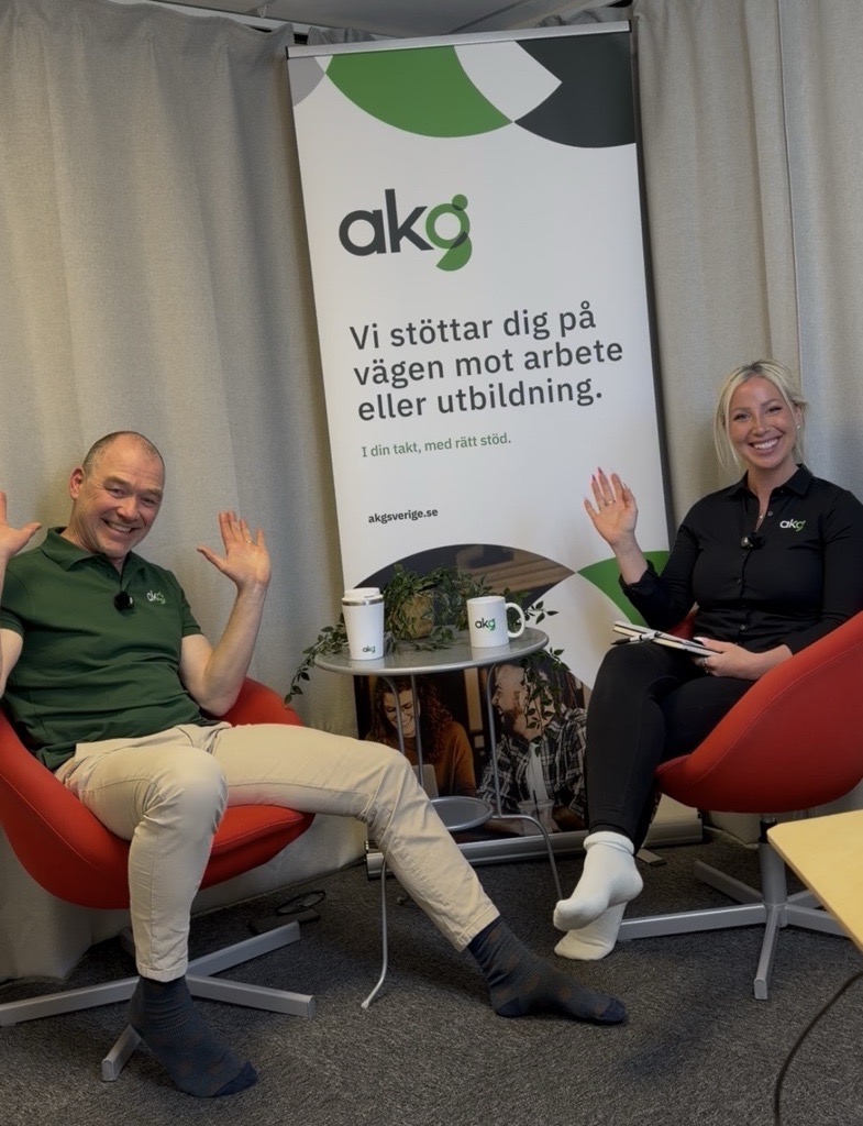 bild på magnus som är podd gäst och anna som är podd ledare. sitter i varsin stol med ett bord emellan och framför en AKG roll up där det står "vi stöttar dig på vägen mot arbete eller utbildning".